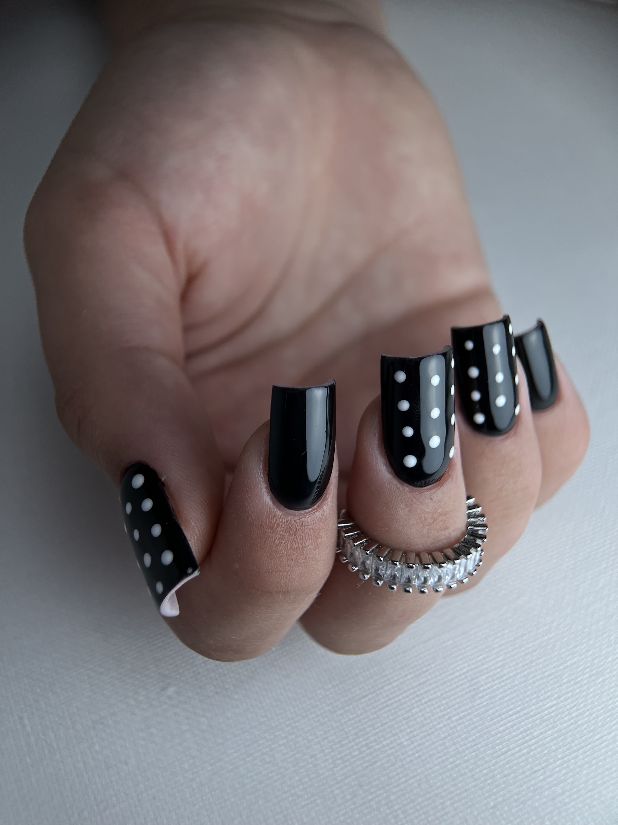 Zwarte manicure met nauwkeurige witte stippen